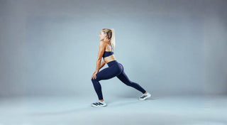Athletin in dunkelblauer Sportleggings und Sport-BH beim Ausfallschritt im Studio.