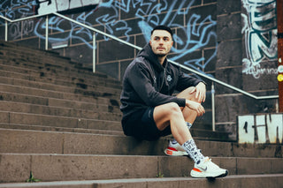 Mann trägt den grauen Gym Hoodie Herren von Lifters Wear und befindet sich draußen in einem Parkhaus