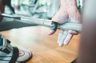 Athlet mit Lifters Hook Grip Tape greift die Langhantel