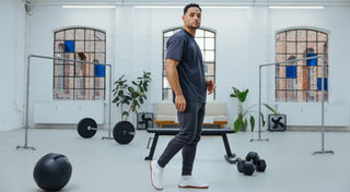 Athlet trägt Lifters Gym Kleidung Herren in schwarz und läuft vor einem Bike Ergometer bereit für sein Training.